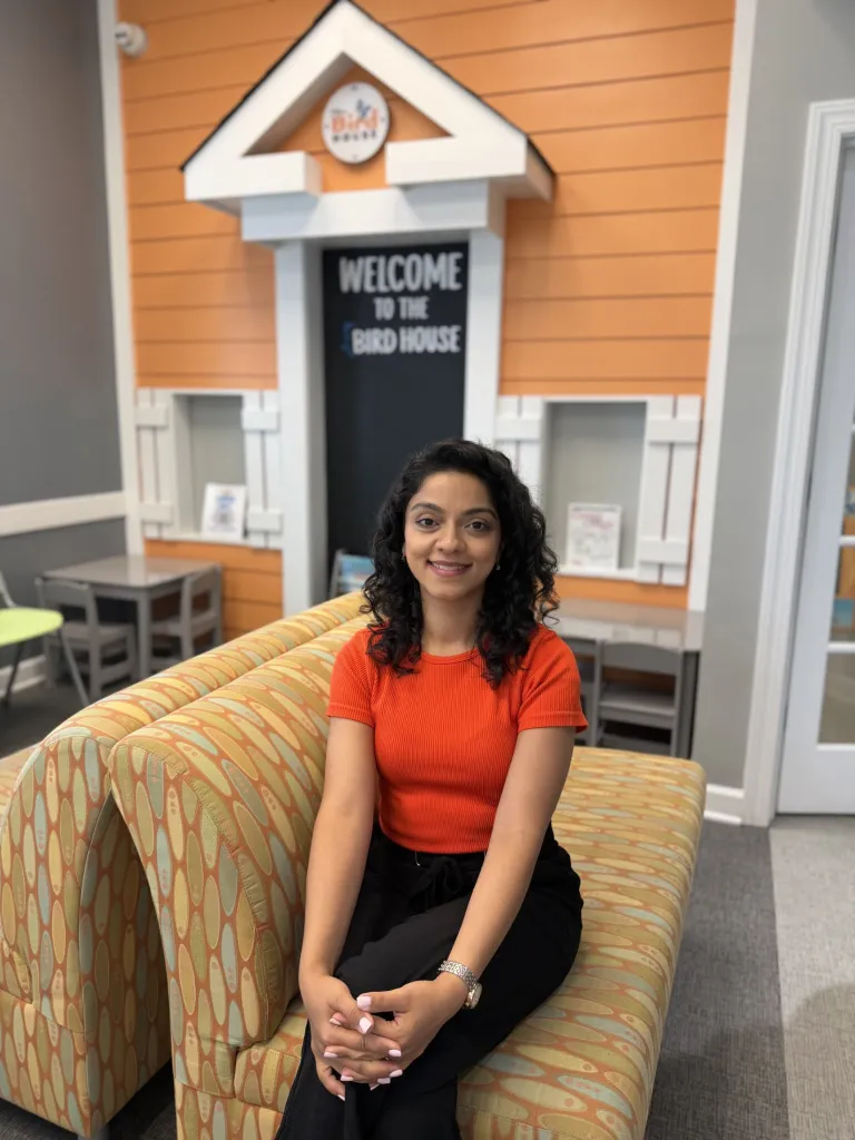Dr. Shekari sitting in Bird Pediatric Dentistry waiting room, smiling at the camera