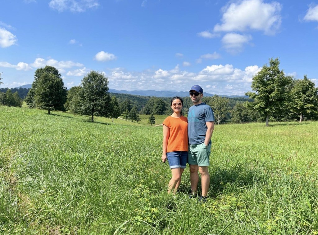 Dr. Shekari and her husband in a green field with mountains in the background